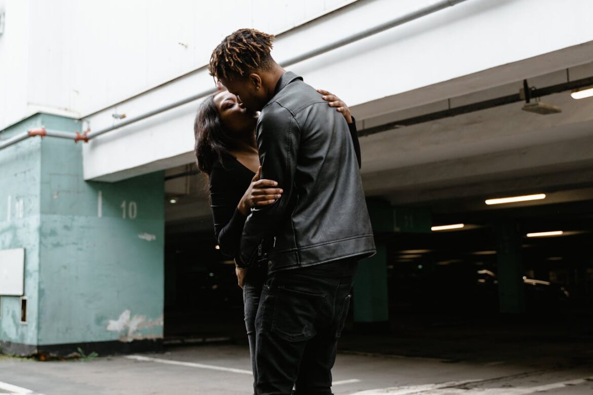 Couple sharing an intimate moment in a modern parking area.